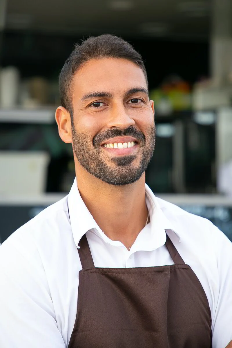 Colaborador con camisa blanca y delantal de trabajo.