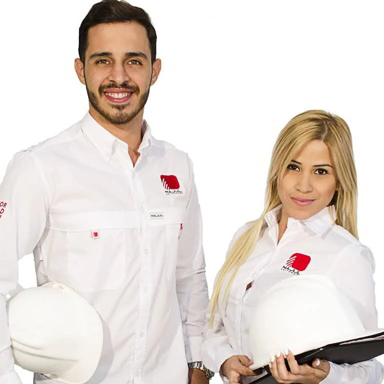 Ver imagen 2 de 2: Dos colaboradores con camisas blancas tipo columbia bordadas, sosteniendo cascos de seguridad.